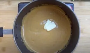 Creamy peanut butter sauce in a saucepan with melting butter, perfect for savory recipes.